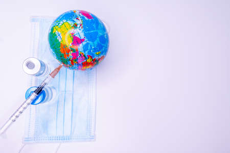 Medical hand injecting a vaccine into planet Earth. Concept of a cure for all people against the...