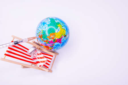 Vaccination certificate with a vaccine bottle, syringe immunization document, a face mask International traveling in the medical mask on world mapの写真素材