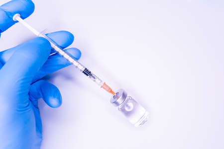 flu and pandemic vaccines, syringe and vial with red liquid on a blue background. medical concept,...