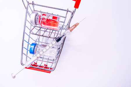 vaccine cost. How much is Covid19 vaccine Injection on blue background with shopping car and money.の写真素材