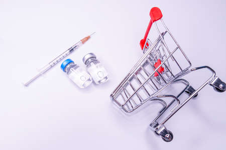 Mini shopping trolley with syringes, injections, vaccines and blood tubes on white background. Vaccination conceptの写真素材