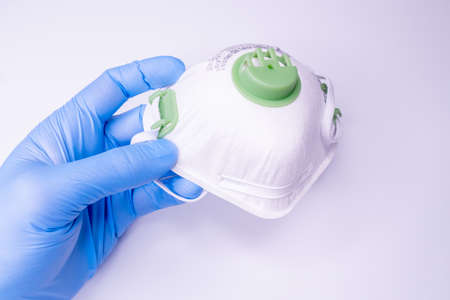 hand holding facial medical mask, white background, close up, copy space, banner. Flu epidemic, allergy season.の写真素材