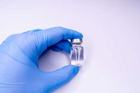 Medicine bottle for injection in hand, palm of a doctor. Medical glass vial for vaccination. Science...