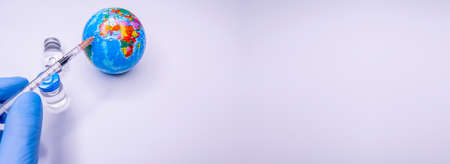 Medical hand injecting a vaccine into planet Earth. Concept of a cure for all people against the coronavirus. Selective focus. Copy Spaceの写真素材