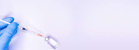 Gloved hand of doctor or nurse holding syringe with liquid vaccine before injecting over white background.Covid19, Coronavirus Concept. Flue shot Copy Spaceの写真素材