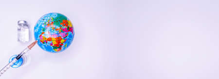 Medical hand injecting a vaccine into planet Earth. Concept of a cure for all people against the coronavirus. Selective focus. Copy Spaceの写真素材