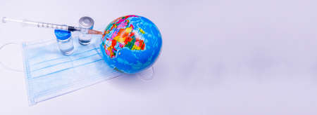Medical hand injecting a vaccine into planet Earth. Concept of a cure for all people against the virus. Selective focus. Copy Spaceの写真素材