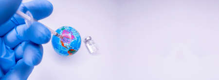 Medical hand injecting a vaccine into planet Earth. Concept of a cure for all people against the virus. Selective focus. Copy Spaceの写真素材