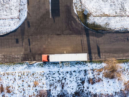 Aerial Follow Shot of White Semi Truck with Cargo Trailer Attached Moving Through Industrial Warehouse, Rural Area.の写真素材
