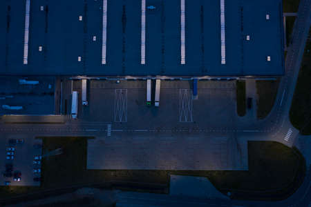 Aerial view of goods warehouse at Night. Logistics center in industrial city zone from above. Aerial...