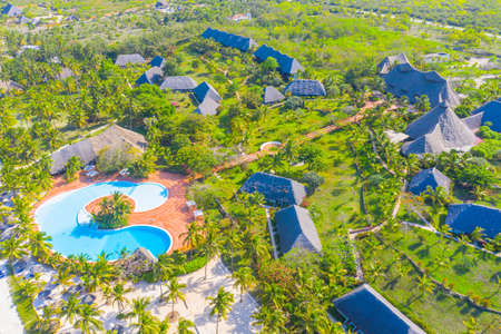 Aerial view of tropical sandy beach with palms and umbrellas at sunny day. Summer holiday on Indian Ocean, Zanzibar, Africa. Landscape with palm trees, hotels, pool, white sand, azure sea. Top viewの写真素材