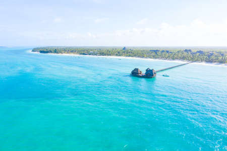 Aerial shot of the Stilt hut with palm thatch roof washed with turquoise Indian ocean waves on the white sand sandbank beach on Zanzibar island, Tanzania.の写真素材