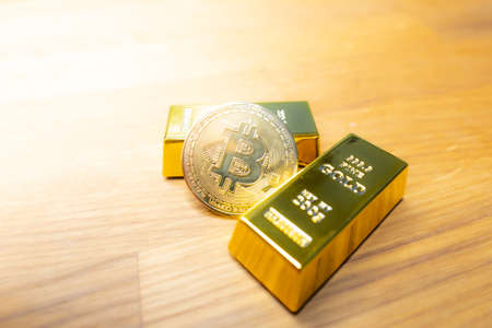 Bitcoin laying on stacked gold bars (gold ingots) rendered with shallow depth of field. Bitcoin as desirable as gold conceptの写真素材