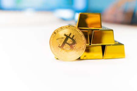 Bitcoin laying on stacked gold bars (gold ingots) rendered with shallow depth of field. Bitcoin as desirable as gold conceptの写真素材