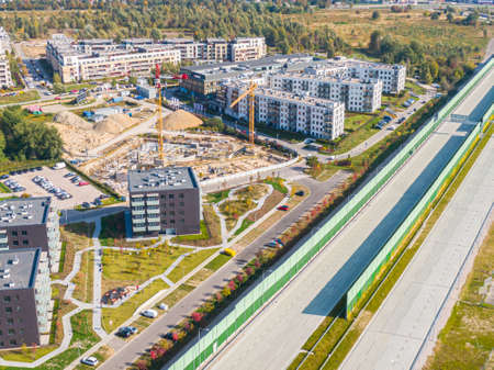 aerial top view of new modern apartment building under construction. yellow cranes working at...