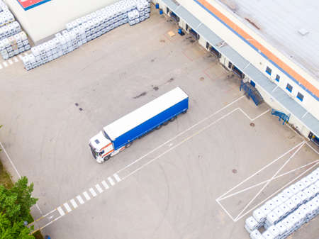Aerial view of goods warehouse. Logistics center delivery in industrial city zone from above. Aerial view of trucks loading at logistic centerの写真素材