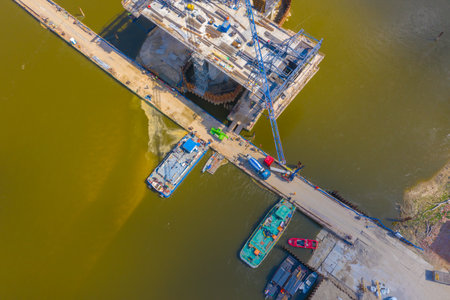 Aerial shot passing over a bridge construction project at sunset in Vistula near Warsaw. Construction of the Most Polnocny bridge. Polandの写真素材