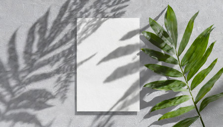 vertical sheets of textured white paper against a soft gray table background. the natural light creates subtle shadows from an exotic plant, enhancing the mockup overlay in a horizontalの素材