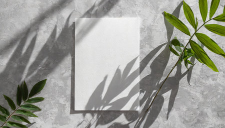 vertical sheets of textured white paper against a soft gray table background. the natural light creates subtle shadows from an exotic plant, enhancing the mockup overlay in a horizontalの素材