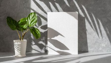 vertical sheets of textured white paper against a soft gray table background. the natural light creates subtle shadows from an exotic plant, enhancing the mockup overlay in a horizontalの素材