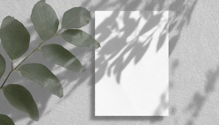 vertical sheets of textured white paper against a soft gray table background. the natural light creates subtle shadows from an exotic plant, enhancing the mockup overlay in a horizontalの素材