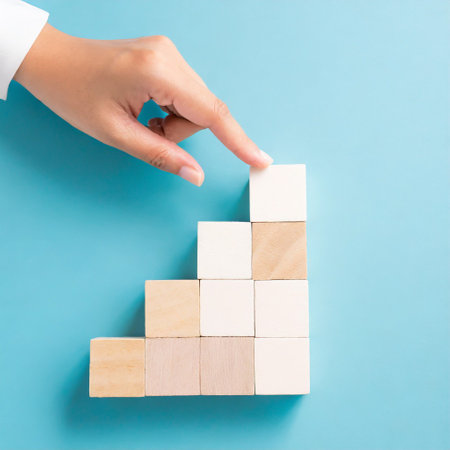Business concept growth success process, Close up Woman hand arranging wood block stacking as step stair on paper blue background, copy space.の素材