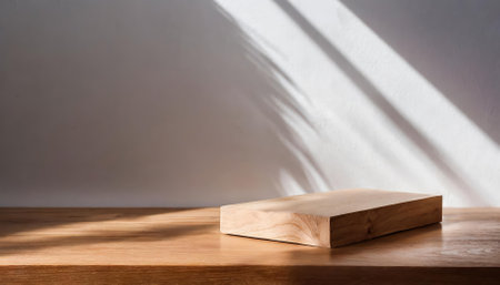 An empty wooden table podium in a minimalist natural setting, featuring sunlight and shadow interplay with green accents, ideal for showcasing products, modern designs, or aesthetic photographyの素材