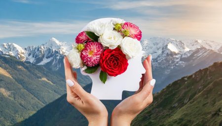 Artistic portrayal of hands holding a paper head featuring a human brain adorned with vibrant flowers, emphasizing self-care, emotional well-being, mental health growth, and mindfulness in aの素材