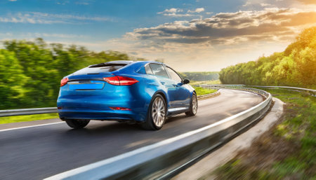 An elegant blue business car rushes at high speed along a curved highway, showing its advanced design and performance. This stunning motion shot highlights speed, agility, and urbanの素材