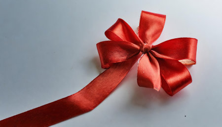 A stunning image showcasing a bright red bow placed on a clean, white background. This minimalist composition emphasizes elegance and festive charm, making it ideal for seasonal, decorative, orの素材
