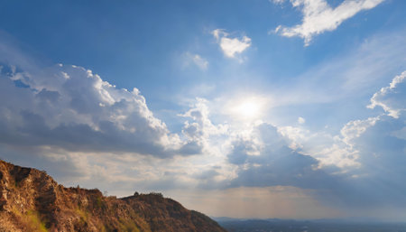 This image captures the radiant beauty of a sunlit blue sky adorned with scattered clouds of varying sizes, blending tranquility and vibrancy to reflect the serene essence of nature's perfection.の素材