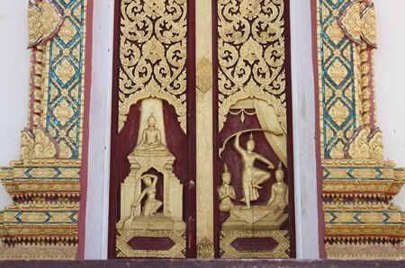 Thai art carving and painting on door of templeの写真素材