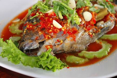 Fried fish topping with chili sauce and mixed green vegetables saladの写真素材