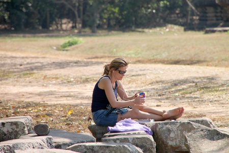 SIEMREAP, KHMER REPUBLIC - FEBRUARY 11 : The unidentified woman is relaxing sitting on the rock on February 11, 2012 at Angkor Wat, Siemreap, Khmer Republic.のeditorial素材
