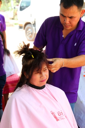 NACHUAK, MAHASARAKHAM - MARCH 21 : The unidentified barber is cutting an old woman hair in public secter services mobile project on March 21, 2012 at Nong Bua Daeng school court, Nachuak, Mahasarakham, Thailand.のeditorial素材