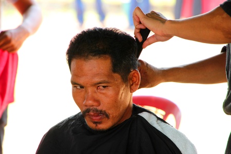 NACHUAK, MAHASARAKHAM - MARCH 21 : The unidentified barber is cutting an old man hair in public secter services mobile project on March 21, 2012 at Nong Bua Daeng school court, Nachuak, Mahasarakham, Thailand.のeditorial素材
