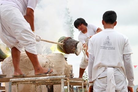 NACHUAK, MAHASARAKHAM - APRIL 28 : Unidentified Buddhists are pouring liquid brass into Buddha mold...