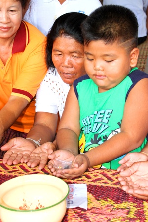 NACHUAK, MAHASARAKHAM - APRIL 28 : Unidentified Buddhists are given sacred objects by monk in ceremony of pouring liquid brass into Buddha mold on April 28, 2012 at Wat Hua Sra, Nachuak, Mahasarakham, Thailand.のeditorial素材