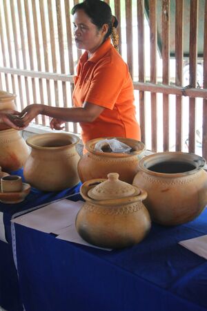 MUANG, MAHASARAKHAM - SEPTEMBER 13 : Unidentified woman is selling earthenware pots to group of tourists on September 13, 2012 at Ban Moh (Pottery village), Muang, Mahasarakham, Thailand.のeditorial素材