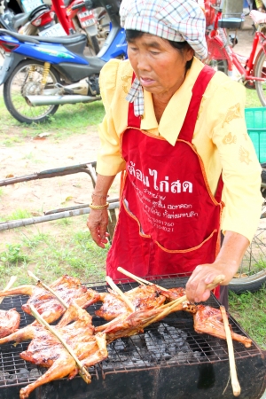 MUANG, MAHASARAKHAM - SEPTEMBER 19 : Unidentified woman is selling grilled chicken in public secter services mobile project on September 19, 2012 at Wat Don Whan, Muang, Mahasarakham, Thailand.のeditorial素材