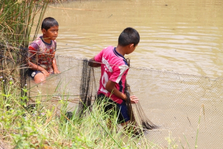 NACHUAK, MAHASARAKHAM - APRIL 5 : Unidentified boys are catching freshwater fishes on April 5, 2012 at local reservoir, Nachuak, Mahasarakham, Thailand.のeditorial素材