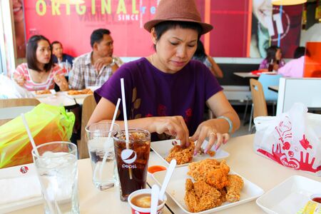 MUANG, MAHASARAKHAM - DECEMBER 1 : Unidentified woman is eating fast foods on December 1, 2012 at Big C super market, Muang, Mahasarakham, Thailand.のeditorial素材