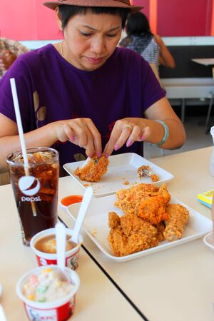 MUANG, MAHASARAKHAM - DECEMBER 1 : Unidentified woman is eating fast foods on December 1, 2012 at Big C super market, Muang, Mahasarakham, Thailand.のeditorial素材