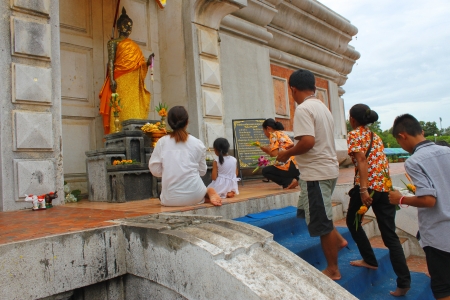 MAHASARAKHAM, THAILAND - JULY 20 : Unidentified girl aged 4 - 5 years and people worship Buddha statue and make religious merit in Buddhist Lent festival at Nadun Pagoda on July 20, 2013 in Mahasarakham, Thailand. のeditorial素材