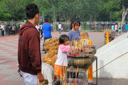 MAHASARAKHAM, THAILAND - JULY 22 : Unidentified child aged 7 years and people light candle and worship Buddha statue at Nadun Pagoda in Buddhist Lent festival on July 22, 2013 in Mahasarakham, Thailand.のeditorial素材