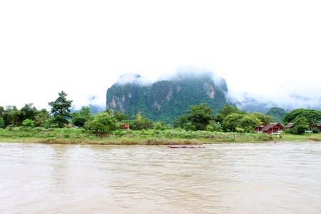 VANG VIENG, LAO P D R  - AUGUST 24   Unidentified tourists are traveling on long-tailed boat trip in Song River on August 24, 2013 in Vang Vieng, Lao P D R  Long-tailed boat has a small motor driving a propeller at the end of a long shaft のeditorial素材
