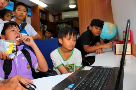 MAHASARAKHAM - SEPTEMBER 24   Unidentified children aged 7-12 years are playing video game from public mobile library at Nong Ku village on September 24, 2013 in Muang Mahasarakham, Thailand のeditorial素材