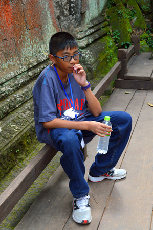 SIEM REAP, CAMBODIA - NOVEMBER 24   Unidentified boy aged 14 years takes a rest at one corner of ancient The Ta Prohm in Angkor Thom on November 24, 2013 in Siem Reap, Cambodia のeditorial素材