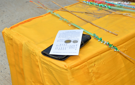 NA DUN, MAHASARAKHAM - APRIL 7   Fortune paper and coins are laid on the table after cast lots in Buddhist holy day at Na Dun pagoda on April 7, 2014 in Mahasarakham, Thailand のeditorial素材