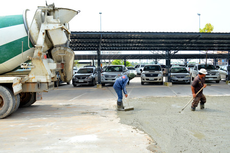 MAHASARAKHAM - OCTOBER 8 : Masonry workers repair concrete parking floor at Sermthai complex on October 8, 2014 in Mahasarakham, Thailand.のeditorial素材